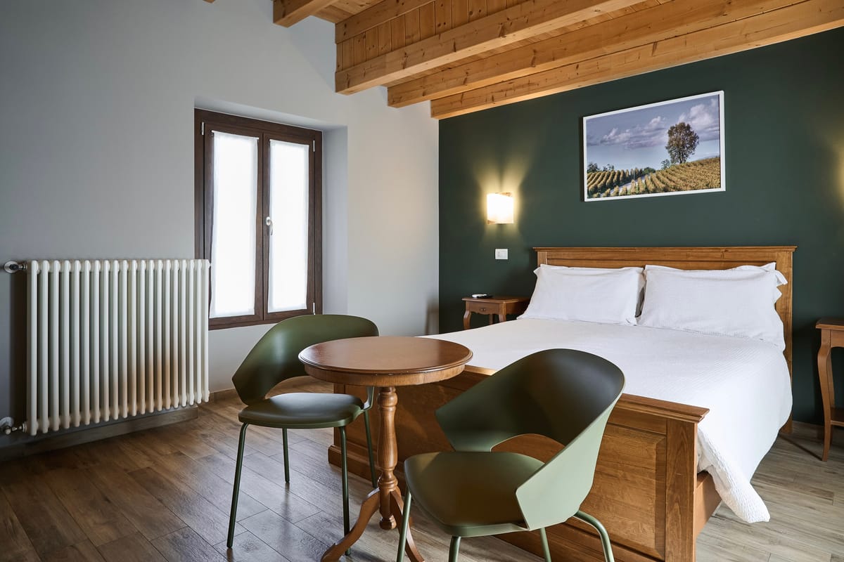 Room with a green wall, double bed and small table